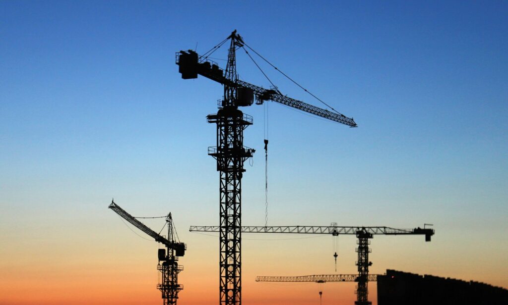 Tower cranes over a construction site at dusk, construction site security Chicago