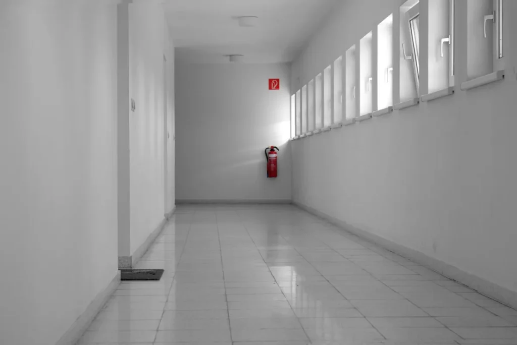 Empty building hallway with a wall-mounted fire extinguisher, patrolled by fire watch guards in Chicago
